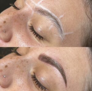 A woman with brown hair and black eyes is getting her brows tattooed.