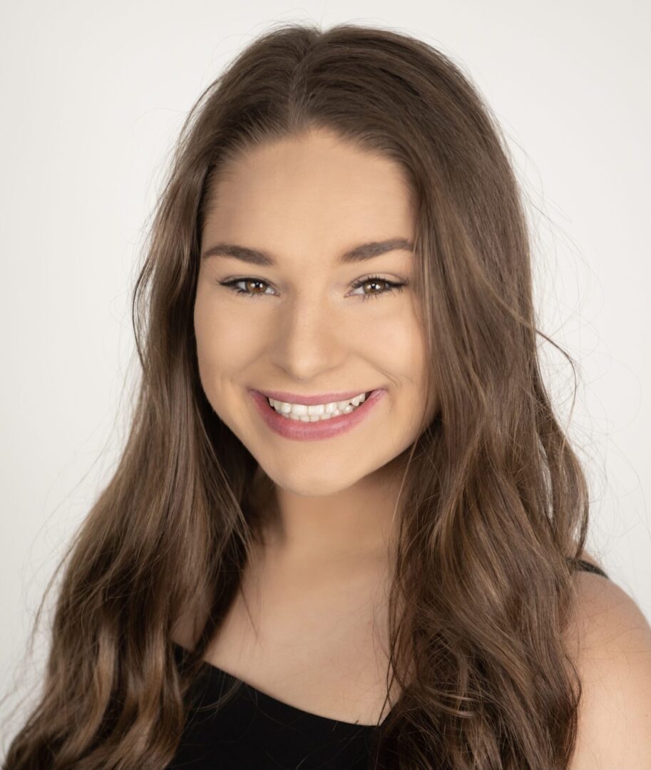 A young woman with long hair smiles for the camera.