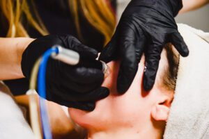 A person getting their ear waxed by an esthetician.