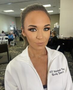 A woman in white jacket standing next to a table.