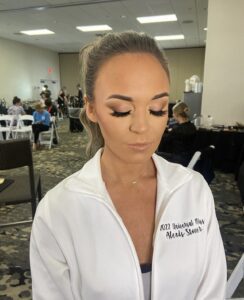 A woman with long eyelashes and a white jacket.