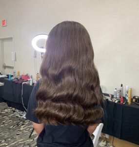 A woman with long hair sitting in front of a mirror.