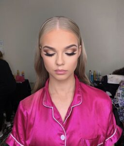 A woman with long blonde hair and cat eye makeup.